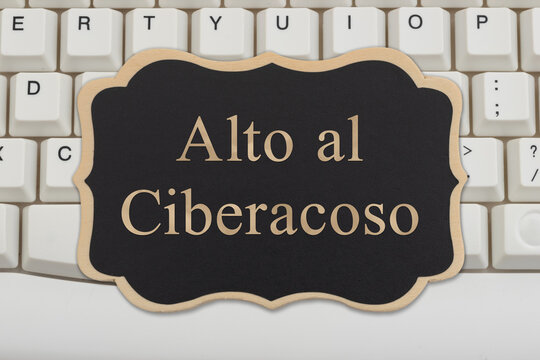 Stop Bullying sign Alto al ciberacoso in Spanish on a chalkboard on a computer keyboard