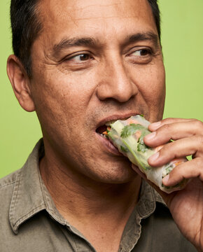 Hearty man bites into an avocado sandwich, with satisfaction with warm, saturated color