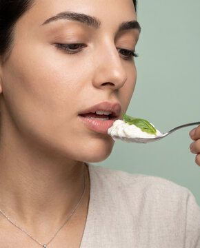 Sensory woman eats a creamy dip with a spoon, and closed eyes with warm, saturated color