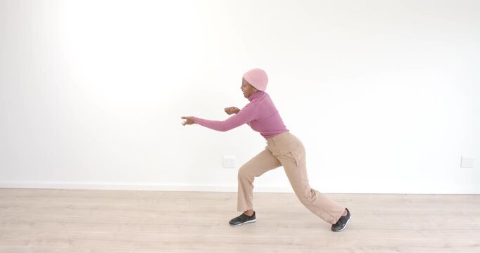 Woman in pink sweater dancing gracefully on wooden floor, expressing creativity