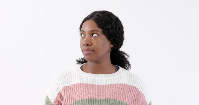 Looking up thoughtfully, African American woman in striped sweater against white background