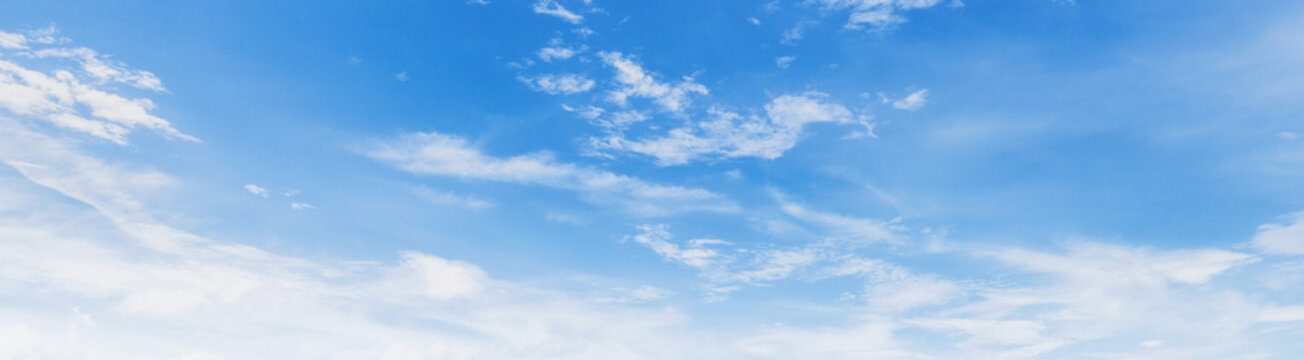 Soft clouds drift across a clear, serene blue sky