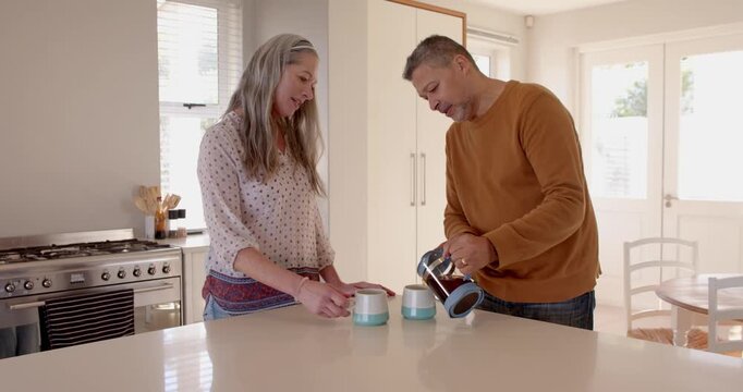 Senior couple enjoying morning coffee together in bright kitchen, sharing happy moment at home