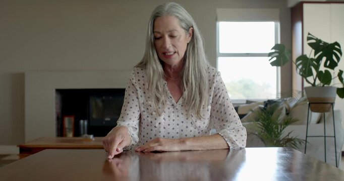 Mature senior woman at home tapping fingers on table, enjoying peaceful moment