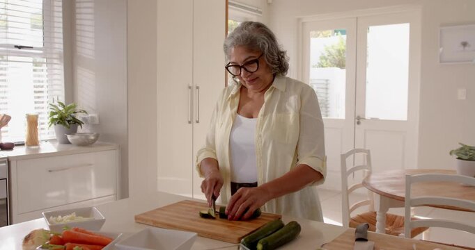 Senior woman chopping vegetables in bright kitchen, preparing healthy meal at home