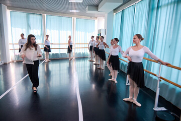 Female ballet coach leads young dancers across bright studio floor © TRAVELARIUM