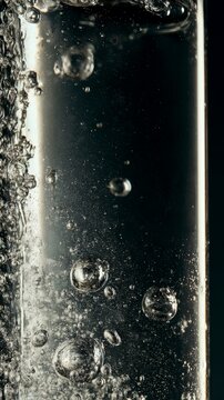 Close-up macro shot of clear liquid with rising bubbles and particles