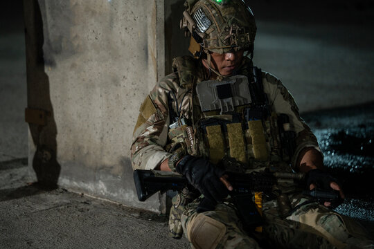 A soldier sits alone in the dark against a concrete pillar, resting quietly during a tense mission. This quiet moment conveys exhaustion, isolation, and deep fatigue during conflict.
