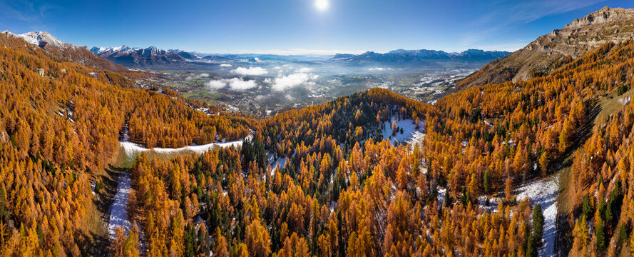 Aerial view of the Champsaur Valley in the French Alps, with colorful autumn larch forests and rugged mountains near the Chaillol ski resort. Hautes-Alpes, France
