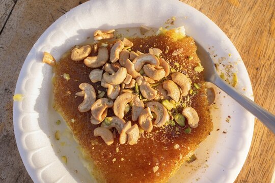 Close up top view Jordan traditional fresh knafeh dessert with melted cheese semolina crust sugar syrup pistachio cashew topping Middle East street food close up