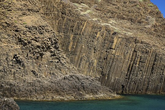 Rock wall with distinct basalt layers merging into turquoise water, Glaronisia, Glaronesia, Milos, islets, hexagonal basalt columns, north of Milos, destination by boat, Cyclades, Greek Islands, Greece
