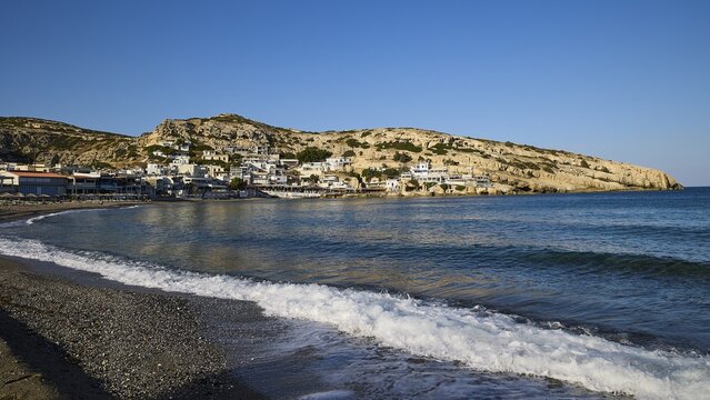 Coastal village on sunny bay with gentle waves on the beach, Matala, South Coast, Crete, Greek Islands, Greece