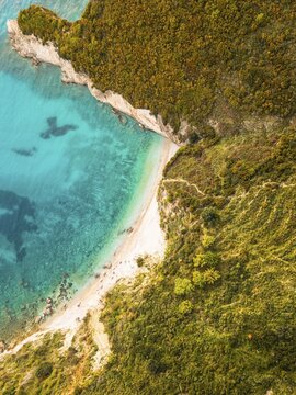 Aerial top down view secluded non commercialized Filikuri rocky beach.Clear turquoise Ionian sea meets steep rocky coastal cliffs. Scenic Albanian Riviera travel landscape in Himar, Albania