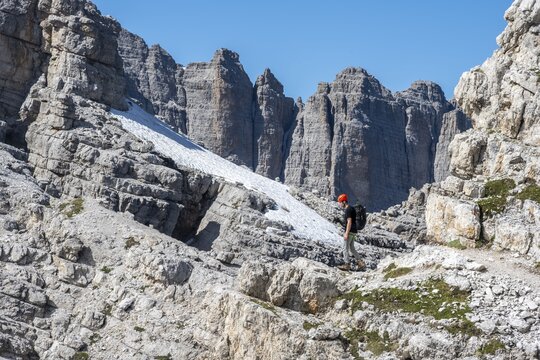 Hiker on a rock band on a steep wall, Brenta Mountains, Brenta-Adamello Natural Park, Trentino, Italy