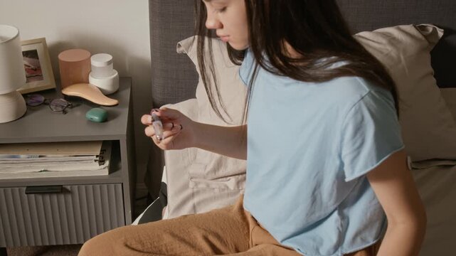 Biracial teenage girl checking glucose reading on smartphone and injecting insulin with medical pen into arm. Suitable for diabetes management and digital health campaigns