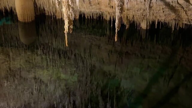 Nature view inside dark dragon cave. Tourist attraction: caves stalactites and stalagmites rock formations blue water lake river. town Porto Cristo Mallorca Spain. vertical video Cuevas del Drach.