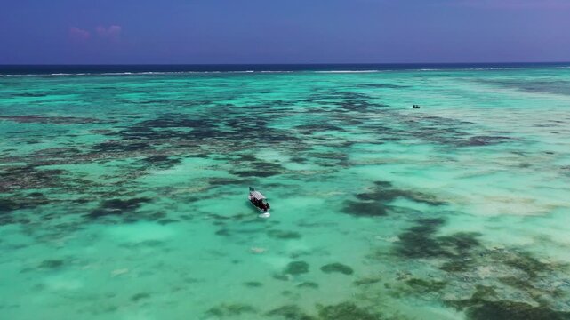 Small boat crossing turquoise lagoon in Zanzibar