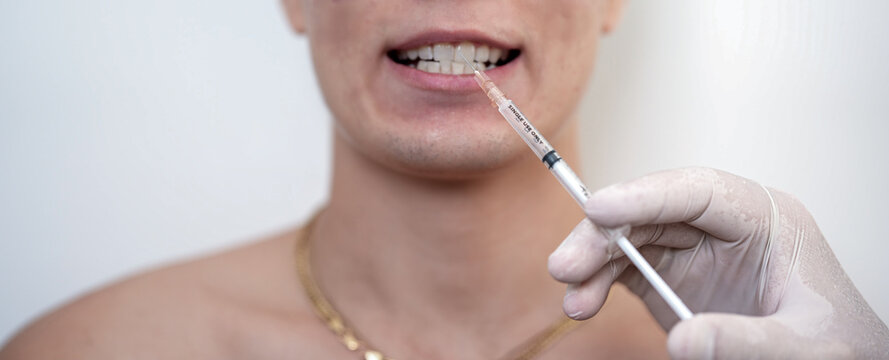 Close-up of a male mouth with a syringe and medical gloved hand. Concept of dental care, local anesthesia, dentistry, aesthetic medicine, cosmetic treatment and healthcare procedures.