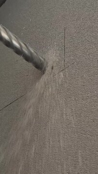 Vertical 9:16 close-up low angle shot of drilling an aerated concrete wall with a thick bit for air conditioning setup.
