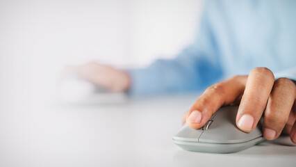 Fototapeta premium Hand of a businessman holding a grey wireless mouse on a white desk with copy space, concept of working with computer, digital technology, online business, and professional productivity.