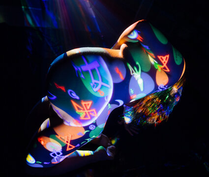Pregnant white woman with colorful projection body art kneeling