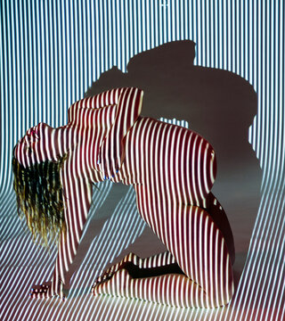 Pregnant white woman kneeling with striped light projection and shadow