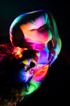 Pregnant white woman with colorful projected light pose