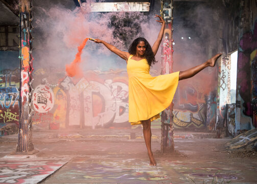 South Asian woman dancing barefoot with smoke flare