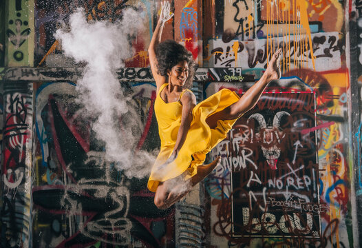 South Asian woman jumping and throwing powder