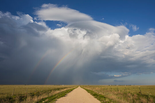 Supercell storm with Double Rainbow over grassland