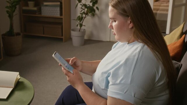 Young Caucasian woman with glucose sensor on arm checking health data on smartphone. Perfect for digital healthcare advertising and diabetes mobile app marketing