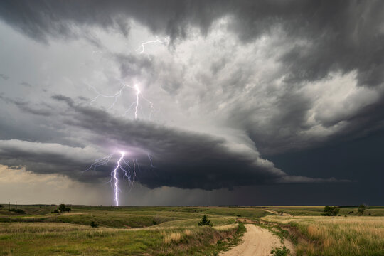 Lightning striking storm cloud over rural road in nebraska grasslands