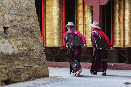 Tibetan women carrying inscribed tablets at Mani Wall prayer wheels