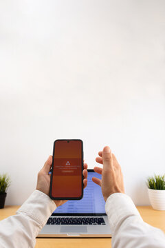 Smartphone showing unusual login alert with laptop email interface in background