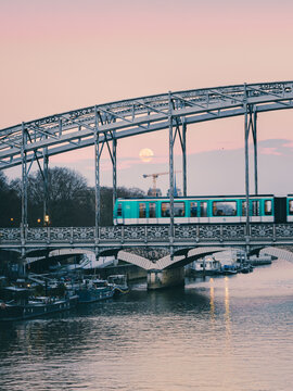 A Parisian metro on the bridge Charles de Gaulle, the moon and the Notre Dame basilic during a winter sunrise