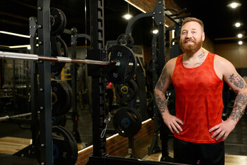 Obraz premium Handsome young man smiles confidently at modern gym while dressed in comfy sportswear