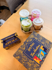 Fototapeta premium Saskachewan, Canada - August 20, 2026: Harry Potter x Tim Hortons limited edition collab drinks and Boite De 10 donut box on wooden table