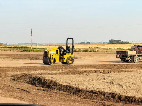 Saskachewan, Canada - August 20, 2026: Yellow Hamm compactor roller compacting soil at rural road construction site on Saskatchewan prairie flatlands