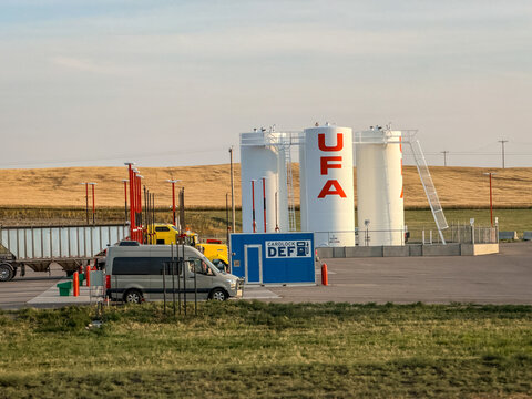 Saskachewan, Canada - August 20, 2026: UFA cardlock fuel station with DEF dispenser, large white storage tanks, and vehicles on Saskatchewan prairie