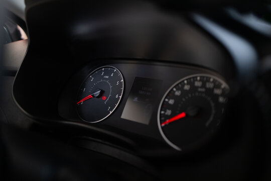 Close up view of a modern automobile instrument panel with illuminated dials and digital display in the dark. Vehicle interior details with speedometer, tachometer, and cockpit elements. Performance