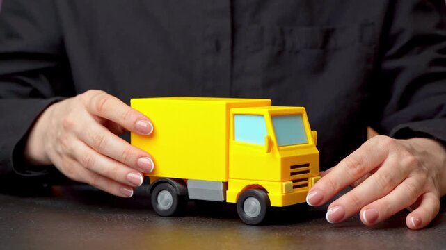 A woman is examining a delivery truck figurine. Delivery and transportation of goods. Logistics networks support global trade. Freight operations ensure timely distribution, supply chain optimization