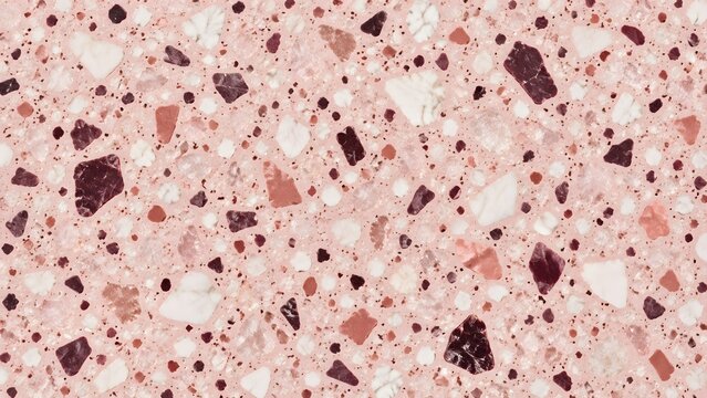 Abstract terrazzo pattern with pink white and dark red chips embedded in a light pink speckled background close up texture