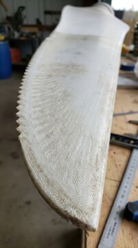 Detailed view of wind turbine blade edge with composite fiber weave and abrasion in a workshop for repair and inspection background