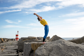 Obraz premium Woman Balancing on Coastal Rocks doing a Yoga Backbend