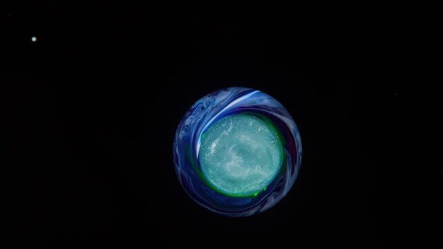 A swirling blue pearlescent drop with a shimmering core, resembling a floating planet in space.