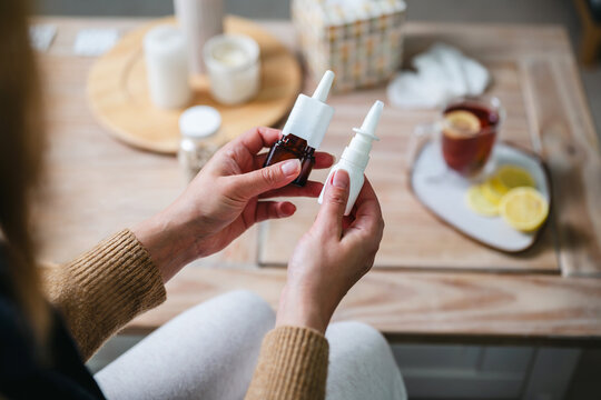 Woman holding two nasal spray bottles at home, seasonal flu, blocked nose and healthcare, medication choice, seasonal allergies concept