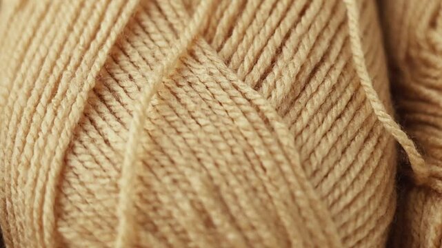 Extreme close-up panning shot across tightly wound beige yarn skeins. Detailed texture of natural wool threads, perfect for crafting backgrounds, textile design, and cozy lifestyle concepts.