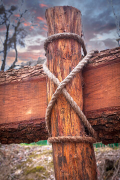 Rustic wooden fence post secured with thick rope against a dramatic cloudy sunset sky background