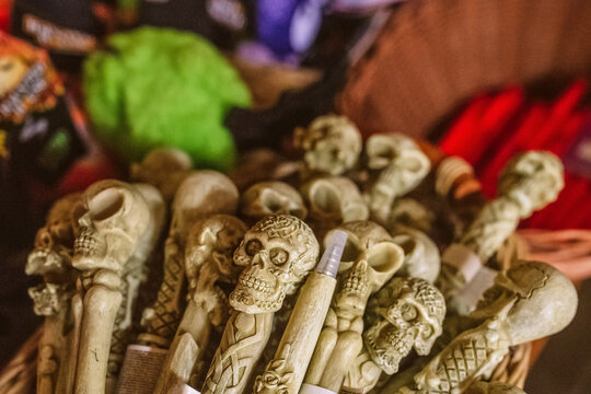 A collection of decorative pens shaped like human skulls and bones displayed in a basket. These novelty items represent gothic style and spooky aesthetics, perfect for Halloween or themed gifts.