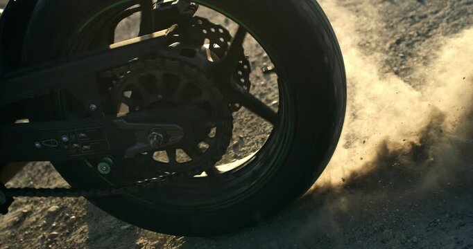 Racing motorcycle skidding on a dirt road, spinning the rear wheel and throwing dust and gravel into the air. Dynamic cinematic action evoking speed, power and adrenaline.